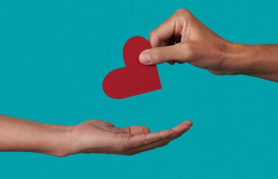 a person giving a red heart to another person on a blue background