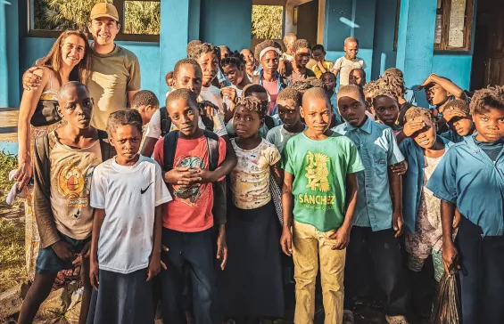 Danny Yadidsion and his wife standing with kids in Africa, where they made a donation to local schools and hospitals