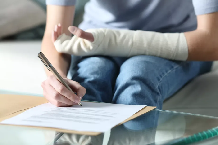 Disabled woman with bandaged arm sigining document